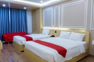 Una habitación de hotel con dos camas y una silla roja. en Hotel Villa Ju, en Hanói 45 fotos más