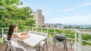 a woman sitting at a table on a balcony overlooking the ocean at Boryeong Thirasel Pension in Boryeong