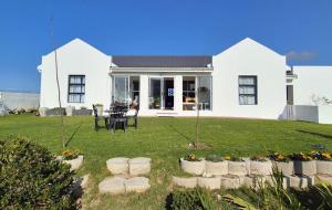 a white house with a lawn in front of it at Corner Rock in Stompneusbaai