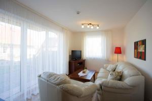 a living room with two white chairs and a television at Villa Boddenblick in Wiek auf Rügen