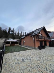 a house with a stone courtyard in front of it at Vila Soleil in Azuga