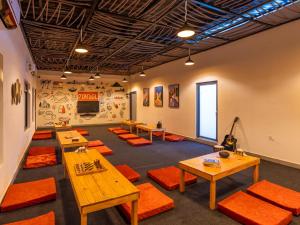 ein Raum mit Tischen und orangefarbenen Polsterstühlen in der Unterkunft The Hosteller Rishikesh, Laxman Jhula in Rishikesh