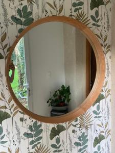 einem runden Spiegel an einer Wand mit einer Pflanze in der Unterkunft L Orée du Bois in Agnetz + 9 Fotos