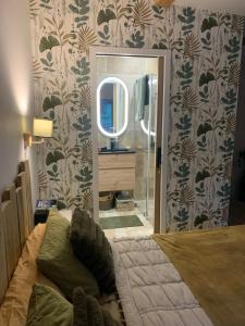 ein Schlafzimmer mit einem großen Bett und einem Spiegel in der Unterkunft L Orée du Bois in Agnetz