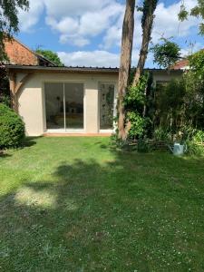 ein Haus mit einem Baum im Hof in der Unterkunft L Orée du Bois in Agnetz