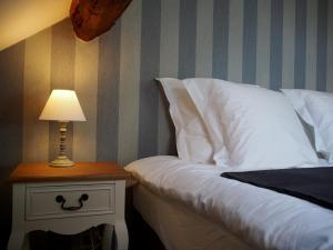 a bed with a table with a lamp on it at Hotel Vorsen in Gingelom