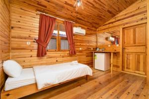 Un dormitorio con una cama en una cabaña de madera. en Izgen Bungalows, en Cıralı