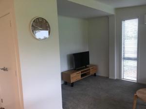 ein Wohnzimmer mit einem TV und einer Uhr an der Wand in der Unterkunft Country Cottage Centrally Located in Tauwhare