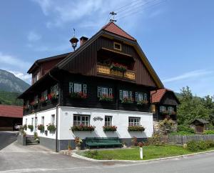 a black and white building with flowers on the windows at Müllnerhof - Familie Maier in Haus im Ennstal