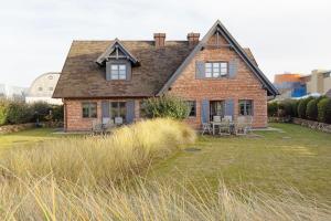 una vecchia casa di mattoni con sedie in un cortile di Strandhafer a List