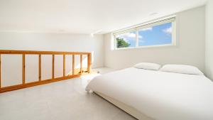 ein weißes Schlafzimmer mit einem Bett und einem Fenster in der Unterkunft Gangneung Lacblanc Pension in Gangneung