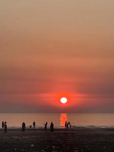 a group of people on the beach at sunset at Golden Wave Cottage in Revadanda