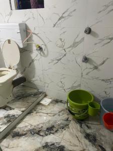 a dirty bathroom with a toilet and a green bucket at Golden Wave Cottage in Revadanda