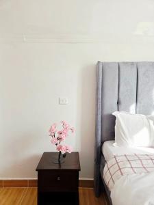 een slaapkamer met een bed en een tafel met roze bloemen bij Homebound stays in Nairobi