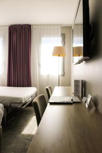 Hôtel Anne De Bretagne في رين: غرفة فندق مع طاولة وسرير