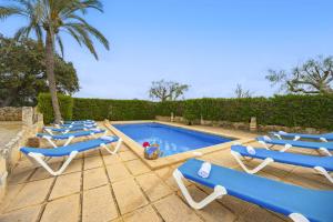 una fila di sedie a sdraio blu accanto alla piscina di Villa Can Granot a Caʼs Concos