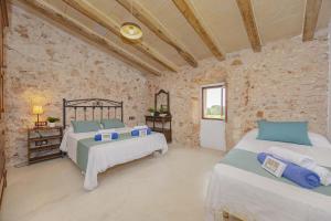 una camera da letto con due letti e un muro di pietra di Villa Can Granot a Caʼs Concos