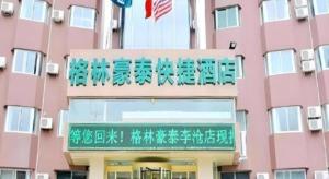 um prédio rosa com escrita chinesa nele em GreenTree Inn Qingdao Licang Shuyan Road Daweng Square Express Hotel em Laoshan