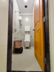 a bathroom with a toilet and a door open at Hotel M R STAY in Mumbai