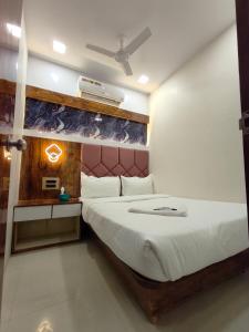 a bedroom with a white bed with a red headboard at Hotel M R STAY in Mumbai
