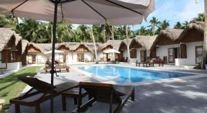 un complejo con piscina con sillas y sombrilla en Elysia Beach Resort, en Donsol