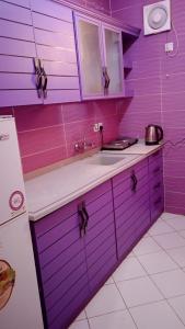 eine Küche mit lila Wänden, einer Spüle und einem Kühlschrank in der Unterkunft أرقى خيال للوحدات السكنية in Chamis Muschait
