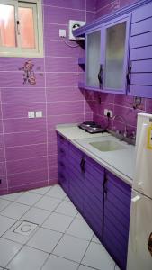 eine lila Küche mit einer Spüle und einem Kühlschrank in der Unterkunft أرقى خيال للوحدات السكنية in Chamis Muschait