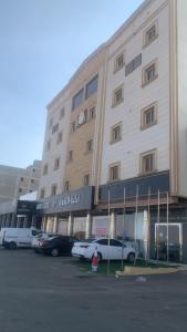 ein großes Gebäude mit auf einem Parkplatz abgestellten Autos in der Unterkunft أرقى خيال للوحدات السكنية in Chamis Muschait