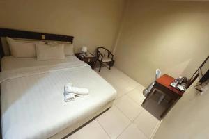 ein Schlafzimmer mit einem weißen Bett und einem Tisch in der Unterkunft Jamilah Inn BilikXpert in Gua Sai