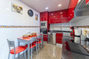 una cocina con armarios rojos y sillas rojas en Magnifico, en Pozuelo de Alarcón