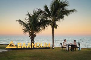 two people sitting at a table in front of the ocean at Mövenpick Asara Resort & Spa Hua Hin in Hua Hin