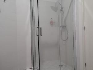 ポルトにあるOporto Downtown Apartmentのシャワーヘッド付きのガラスドアが備わるシャワールームです。