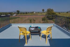 a patio with two chairs and a table on a balcony at SaffronStays Palash in Ane