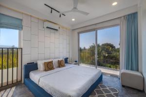 a bedroom with a large bed and a balcony at SaffronStays Palash in Ane +25 photos