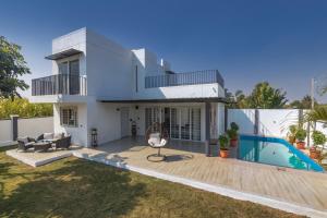 a villa with a swimming pool and a house at SaffronStays Palash in Ane