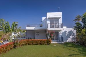 a white house with a balcony and a yard at SaffronStays Palash in Ane