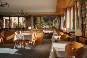 Un restaurante con mesas, sillas y ventanas. en Hotel Bernina, en Pontresina