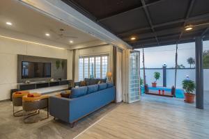 a living room with a blue couch and a television at SaffronStays Palash in Ane