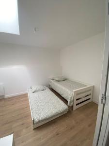 2 letti in una camera bianca con pavimenti in legno di Verdun a Savenay 1 altra foto