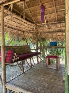Una terraza de madera con un banco en una choza de paja en Himmapun Farmstay, en Ban Pa Ngiu