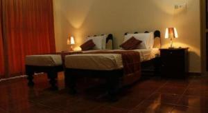 Un dormitorio con dos camas y dos lámparas sobre mesas. en Hotel Lans, en Aswalapitiya