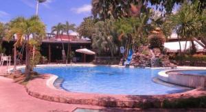 a large swimming pool in a resort with palm trees at The Ritz Hotel at Garden Oases in Cabaguio