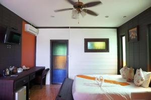 Un dormitorio con una cama, un escritorio y un ventilador de techo. en Wanghin Bungalow, en Ban Na Bo