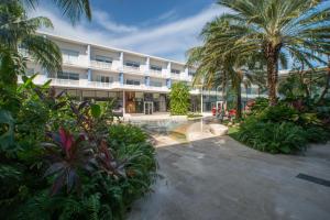 a large building with palm trees and a courtyard at Luxury 1 bed apartment near Seven Mile Beach at The Grove - Villa Nature Bliss in Upper Land