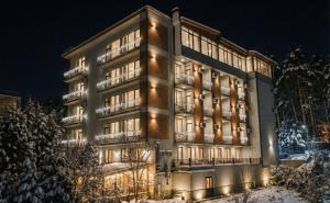 a building with lights in the snow at night at Emerald Borjomi Hotel in Borjomi