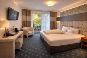 Una habitación de hotel con una cama, un escritorio y un televisor. en Parkhotel an der Therme, en Bad Krozingen