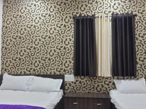 a bedroom with two beds and a patterned wall at Hotel Holiday Era in Aurangabad