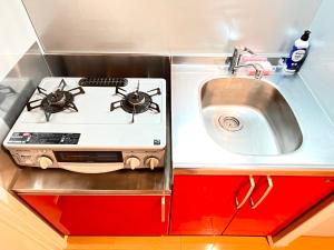 een kleine keuken met een fornuis en een spoelbak bij Camelot House 南福岡 in Fukuoka +42 foto's