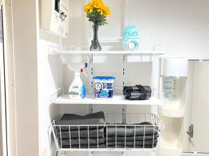 een plank met een vaas van bloemen en andere voorwerpen bij Camelot House 南福岡 in Fukuoka