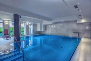 - une grande piscine revêtue de carrelage bleu dans l'établissement Hotel Niemcza Wino & Spa, à Niemcza